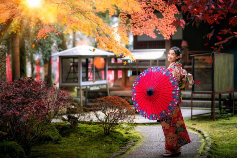 Kvinna vandrar i traditionell japansk trädgård